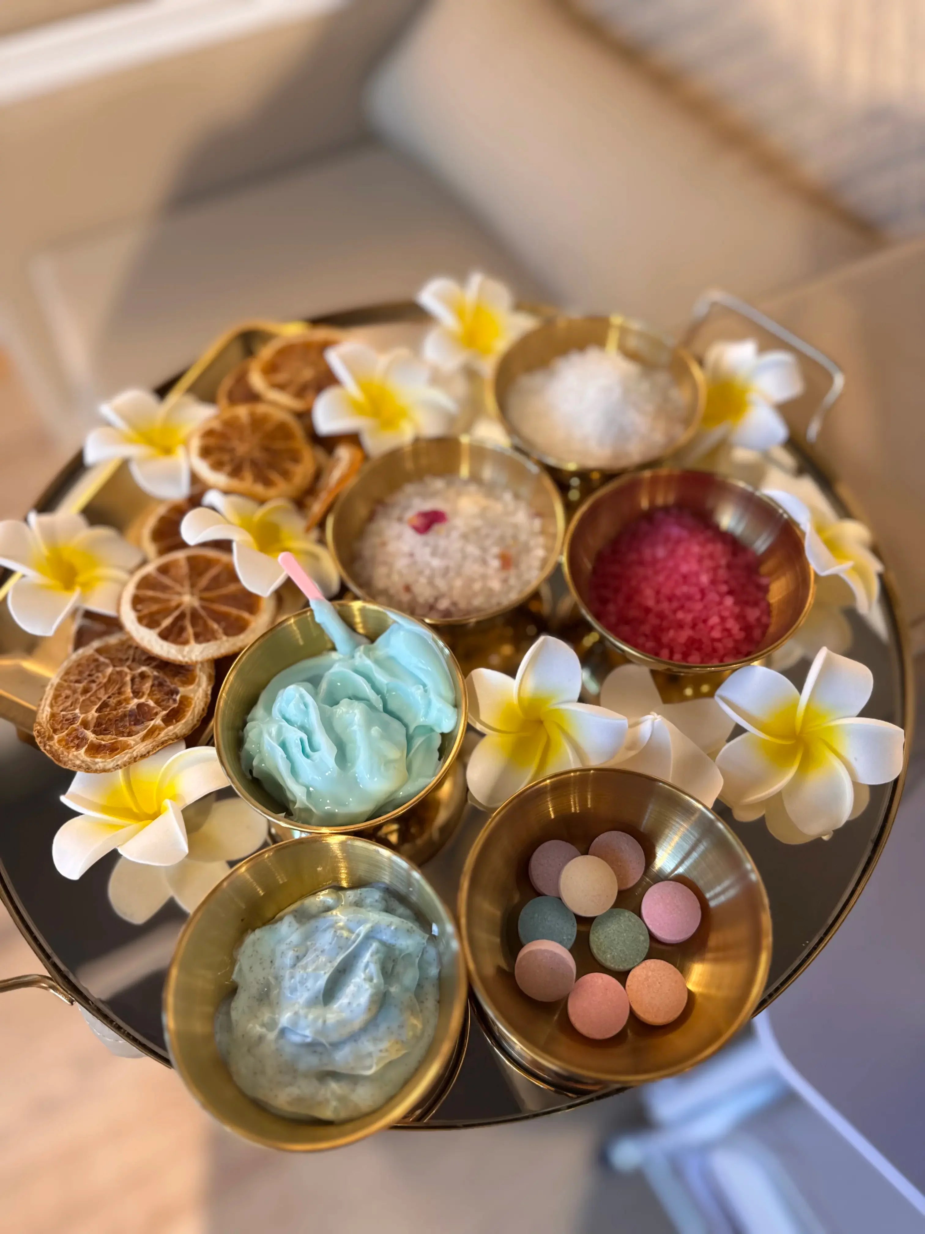 Plateau de soins des pieds avec crèmes bleues, sels de bain colorés, fleurs blanches et rondelles d'agrumes